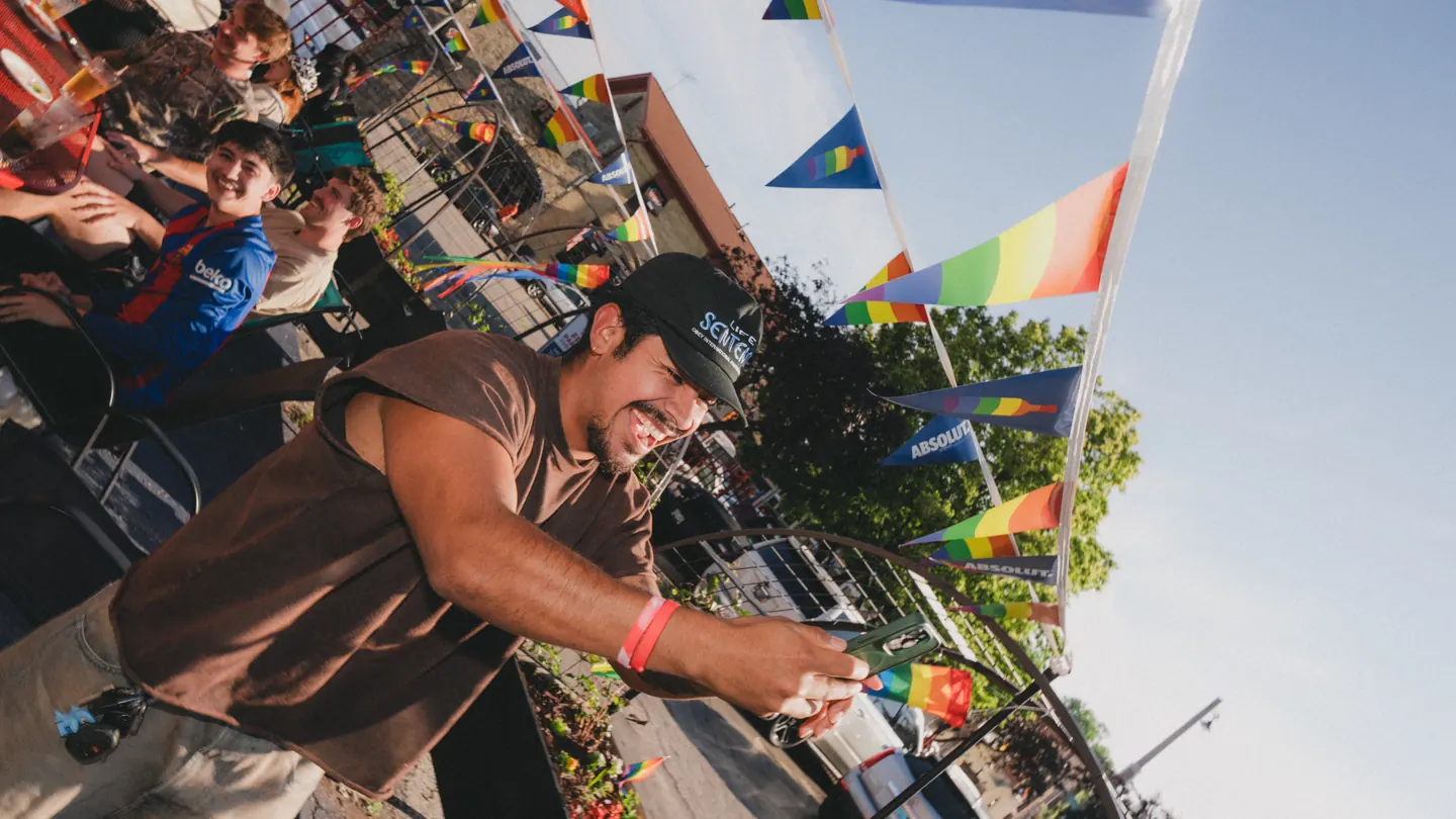 A Summerfest Social participant takes a photo beneath colorful flags.